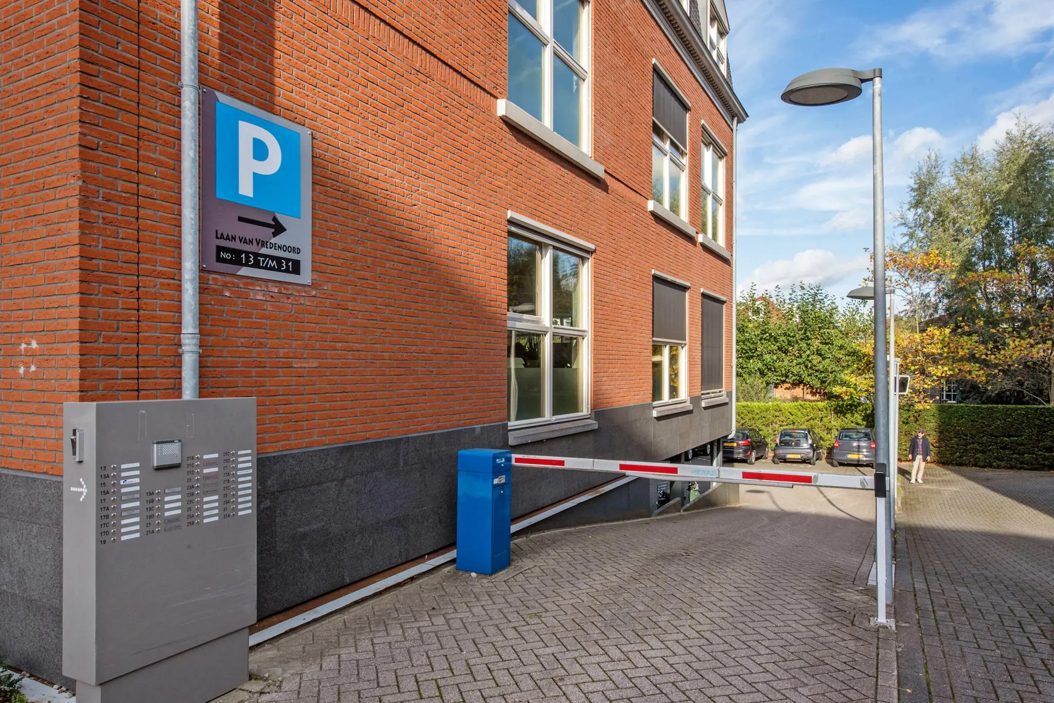 Ingang van een parkeergarage aan de Laan van Vredenoord met slagboom bij een rood bakstenen gebouw.